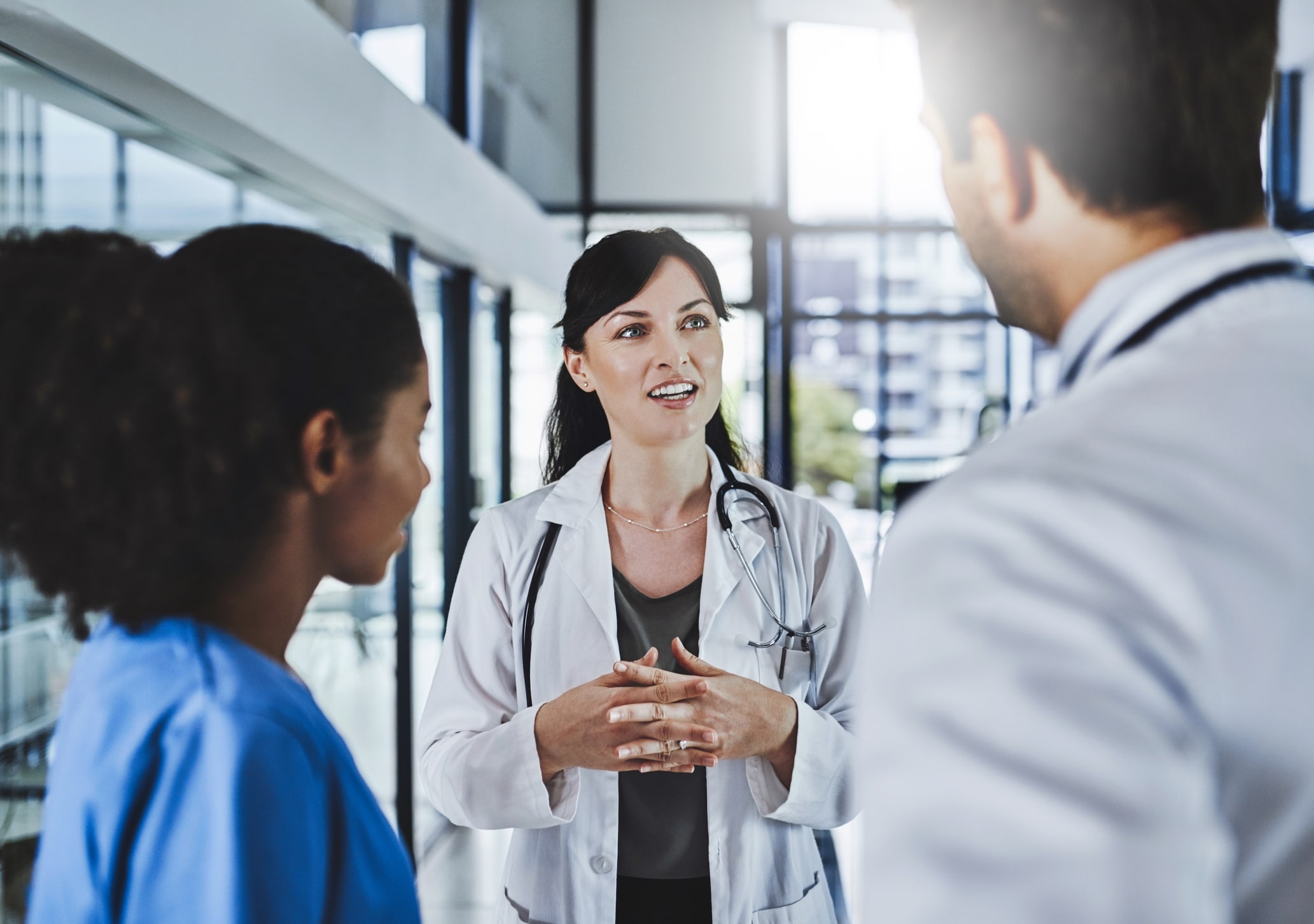 Healthcare organization leader talking to two employees about better engaging with employees