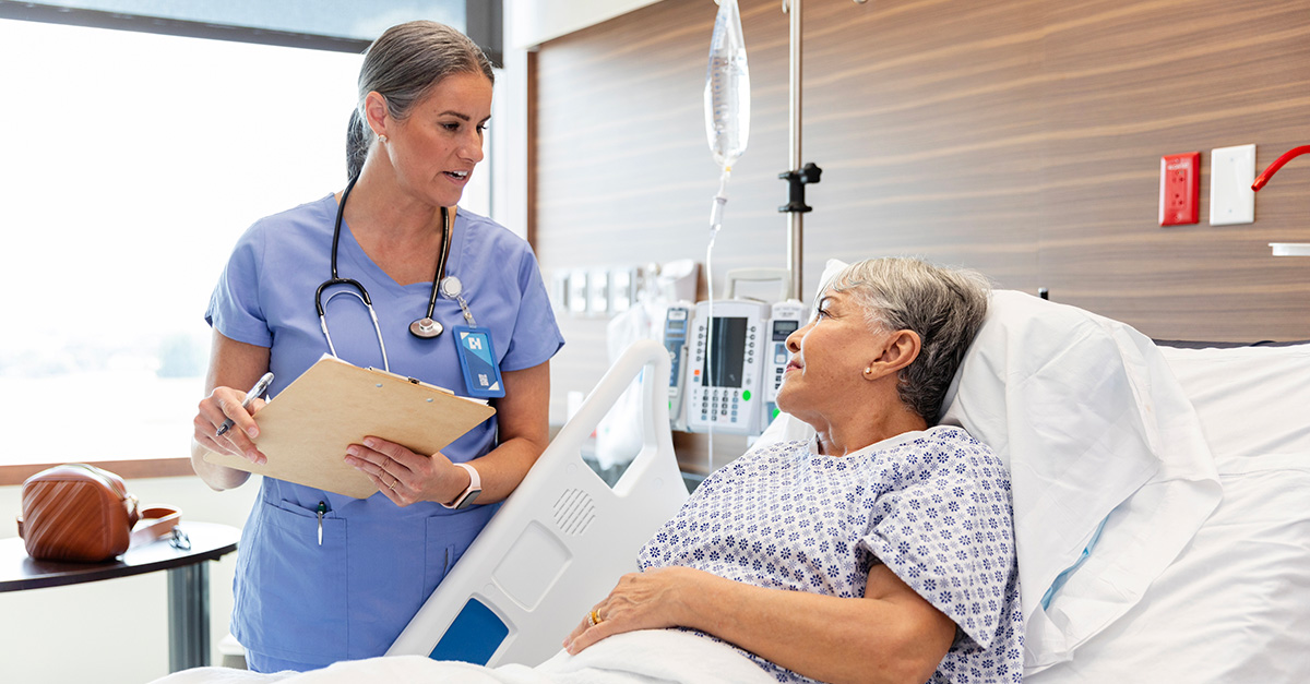 Patient in hospital bed speaking with nurse
